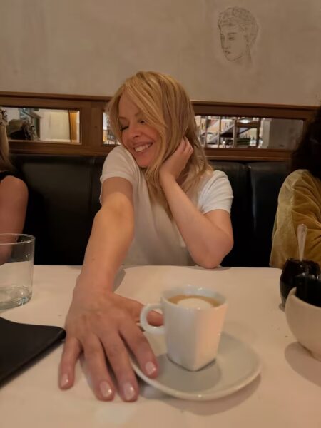 La cantante australiana Kylie Minogue sonríe sentada junto a su equipo de trabajo en una mesa del restaurante de Fernando Trocca en Villa Pueyrredón.